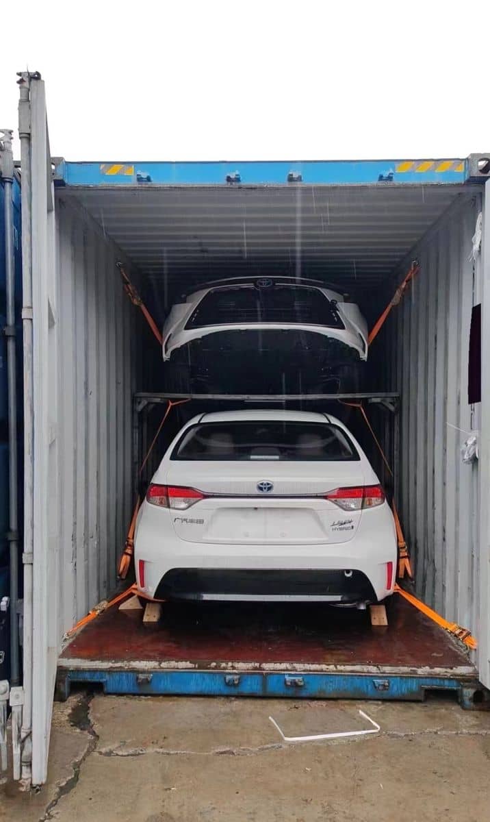 Deux voitures chargées sur des racks à l'intérieur d'un conteneur maritime